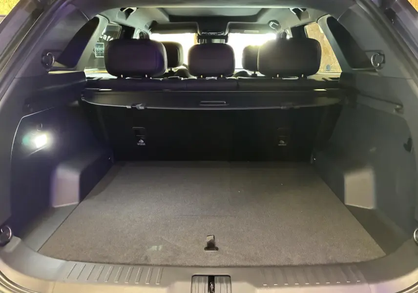 Coffre ouvert vu de l’arrière du JAECOO J7 gris olive, intérieur noir avec banquette arrière et éclairage.