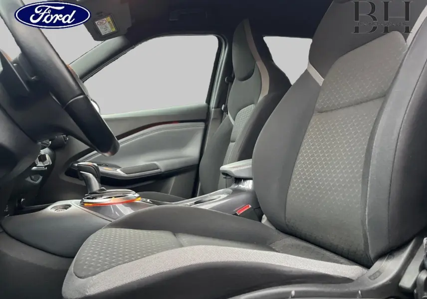 Vue intérieure côté conducteur du Nissan Juke 2020, sièges tissu noir avec surpiqûres grises et console centrale avec levier de boîte automatique.