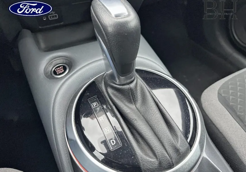 Le levier de vitesse automatique noir en cuir est photographié en gros plan dans l'habitacle d'une Nissan Juke.