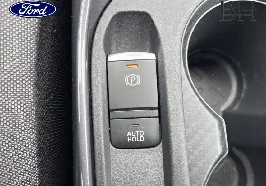 Gros plan sur la commande de frein à main électrique et fonction Auto Hold dans un intérieur noir texturé.