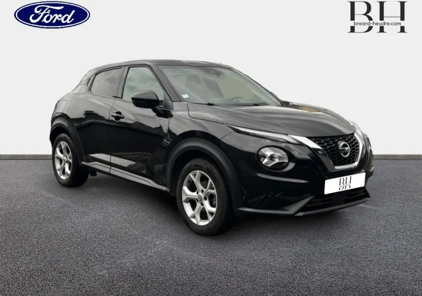 Nissan Juke noir métallisé en 3/4 avant droit, avec jantes alu et calandre distinctive V-Motion.