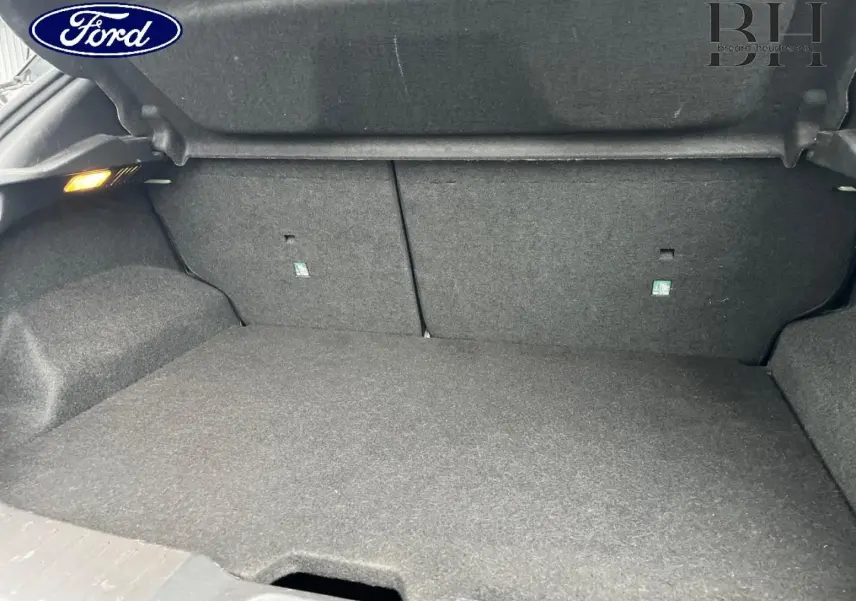 Coffre ouvert d'une Nissan Juke noir métallisé, vue intérieure montrant le tapis de sol et les parois en tissu gris.