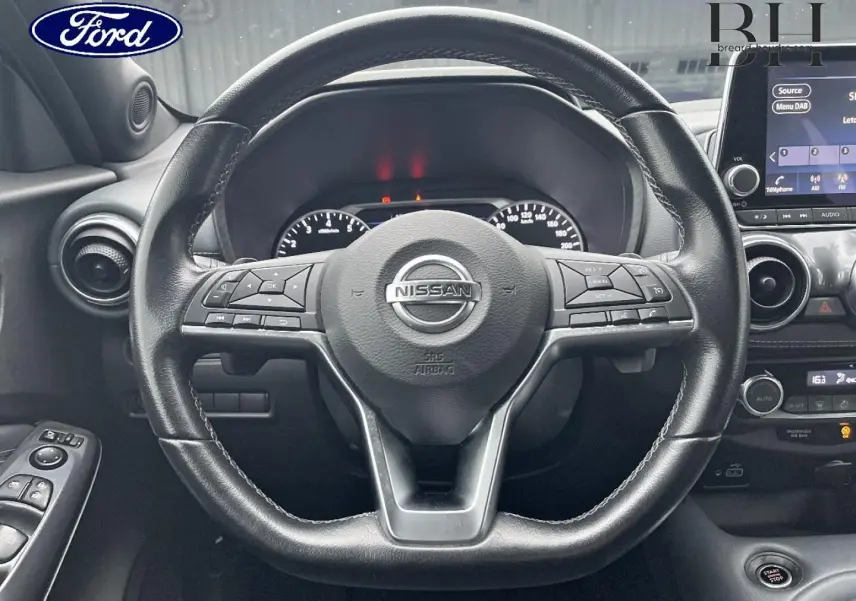 Vue rapprochée du volant cuir noir du Nissan Juke 2020 avec commandes multifonctions et tableau de bord en arrière-plan.