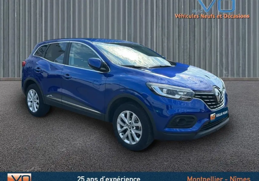 Renault Kadjar TCe 140 Business bleu foncé en 3/4 avant droit, avec jantes alliage et barres de toit visibles.