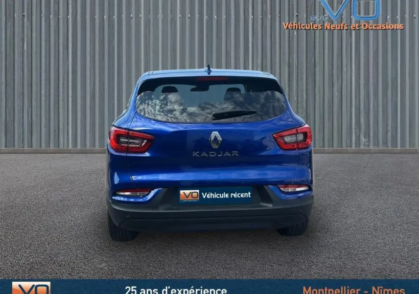 Vue arrière d'un Renault Kadjar bleu foncé 2021 avec feux LED et hayon fermé sur fond industriel.