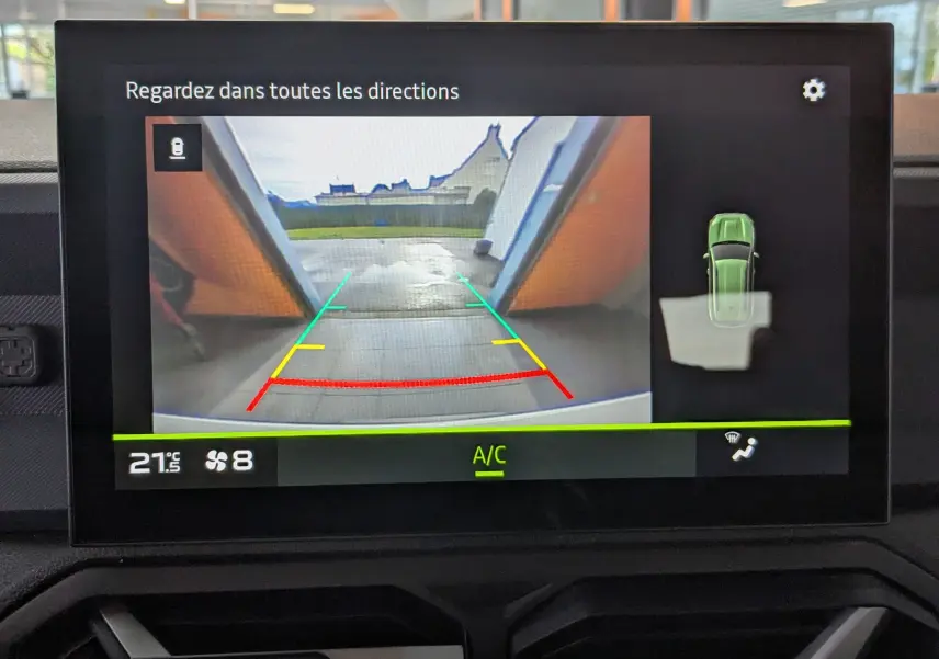 Écran central du Dacia Duster 2025 montrant la caméra de recul avec guidage coloré et vue 360° du véhicule blanc glacier.