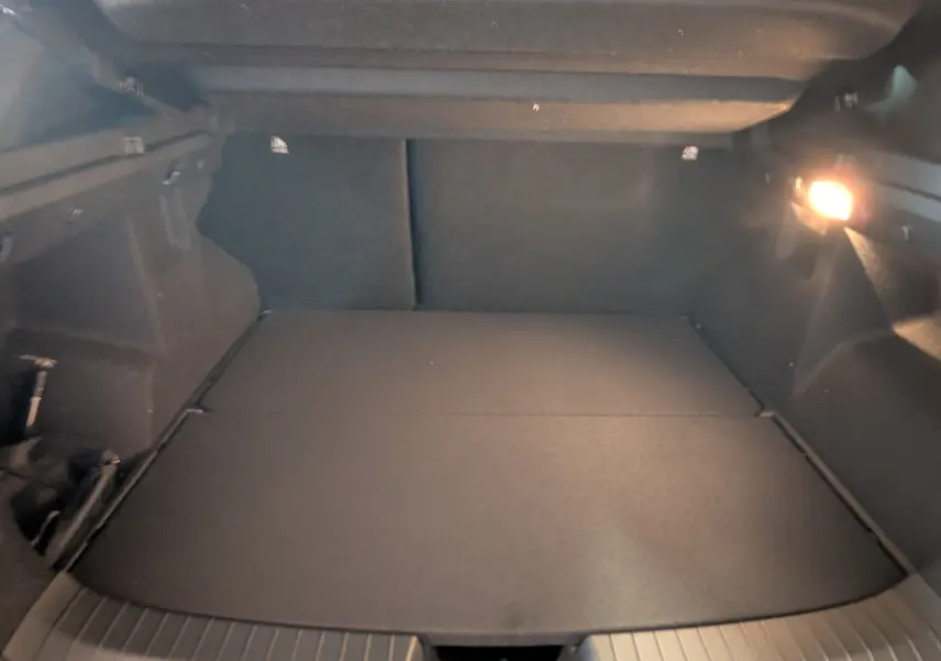 Coffre spacieux du Dacia Duster 1.6 Hybrid 140ch Journey 2025, vue intérieure avec éclairage latéral allumé.