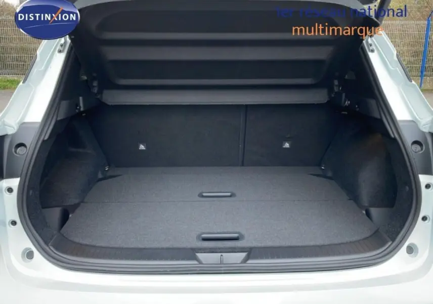 Coffre ouvert vu de l'arrière d'un Nissan Qashqai blanc 2025, montrant un espace de chargement plat et spacieux.