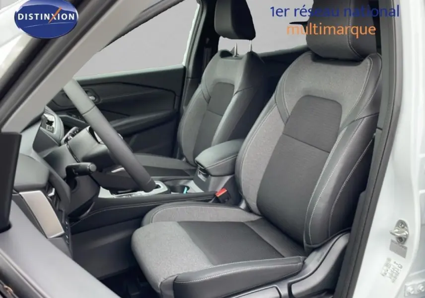 Vue intérieure côté conducteur du Nissan Qashqai blanc 2025, sièges bi-matière gris et noir avec coutures apparentes.