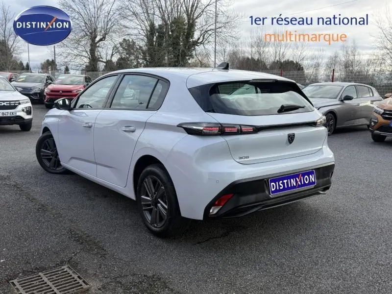 Peugeot 308 blanc Okénite vue 3/4 arrière droit, feux arrière LED distinctifs et logo noir sur hayon.