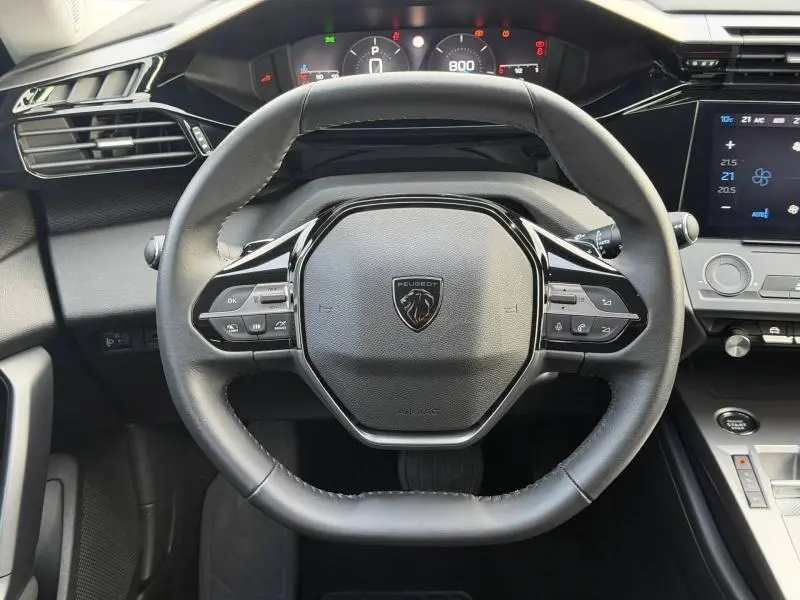 Vue frontale du volant noir de la Peugeot 308 2024 avec tableau de bord numérique et commandes intégrées.