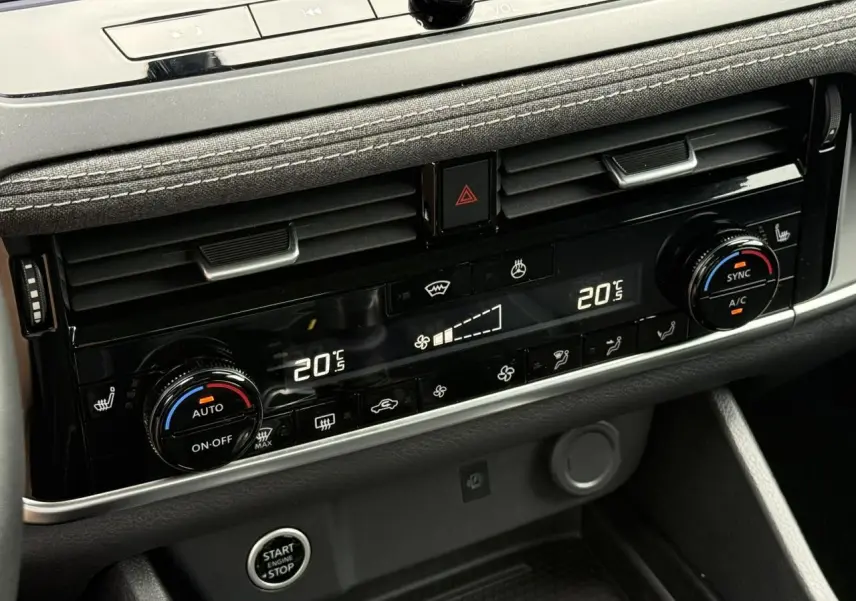 Gros plan sur la console centrale du Nissan Qashqai 2025, affichage digital de la climatisation bi-zone et commandes rotatives.