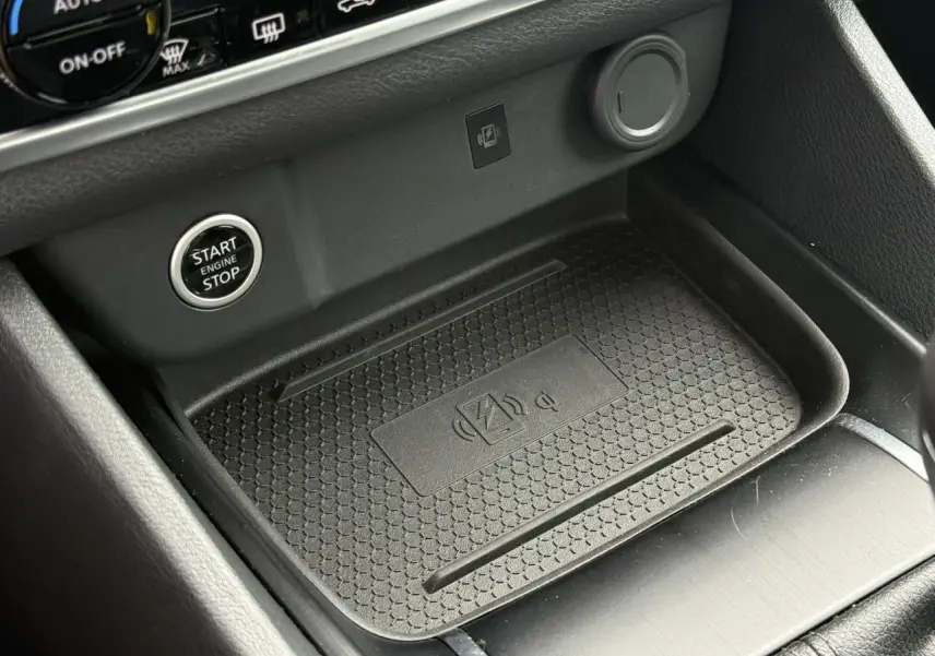 Gros plan sur la console centrale du Nissan Qashqai 2025 bleu Magnétique, montrant le chargeur à induction et le bouton Start/Stop.