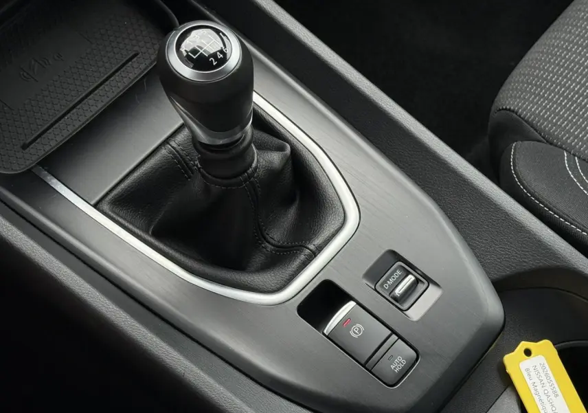 Gros plan sur la console centrale du Nissan Qashqai 2025, mettant en valeur le levier de vitesse manuel et les commandes de frein électrique.