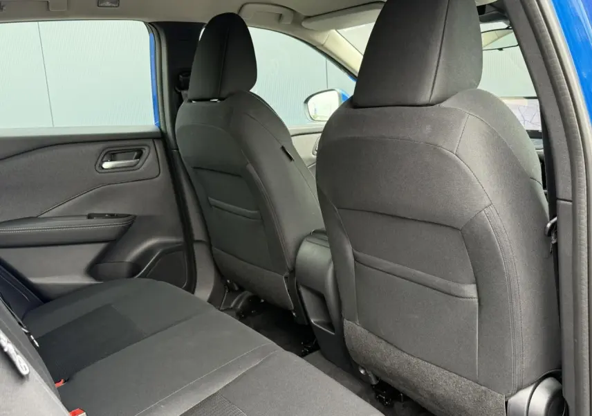 Vue intérieure arrière côté gauche du Nissan Qashqai bleu magnétique, montrant les sièges noirs en tissu.