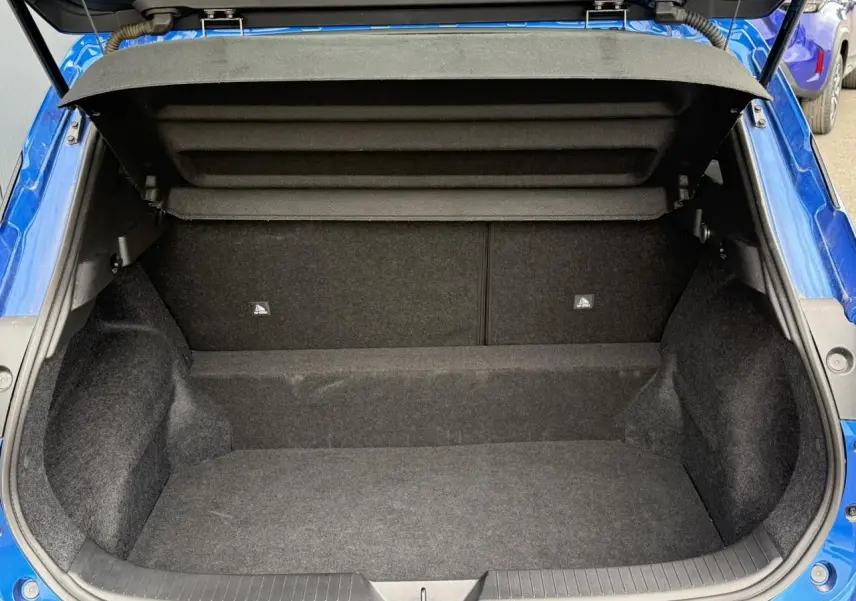 Coffre ouvert vu de l'arrière du Nissan Qashqai bleu magnétique, montrant l'espace de chargement vide et la moquette intérieure.
