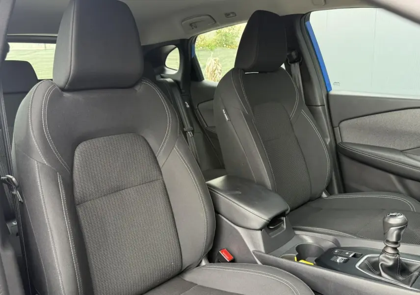 Vue intérieure côté avant droit du Nissan Qashqai 2025 bleu magnétique, montrant les sièges noirs et la console centrale.
