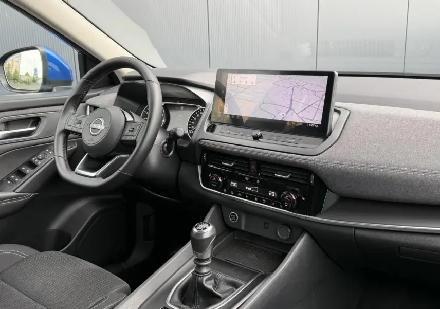 Vue intérieure côté conducteur du Nissan Qashqai 2025 bleu magnétique, avec tableau de bord moderne et écran tactile central.