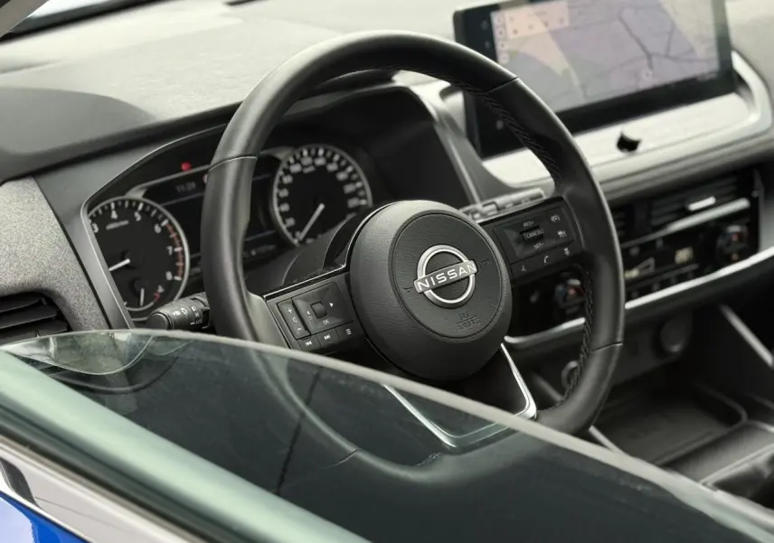 Vue intérieure rapprochée du volant noir Nissan Qashqai 2025 avec tableau de bord et écran tactile visible.