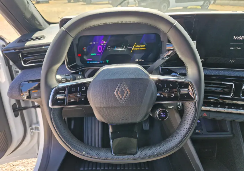 Vue frontale du volant noir perforé de la Renault R5 E-TECH 2025 avec tableau de bord numérique et écran tactile.