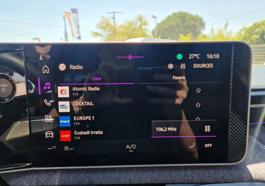 Écran tactile central du Renault R5 E-TECH blanc nacré, affichant la liste des radios FM en intérieur lumineux.