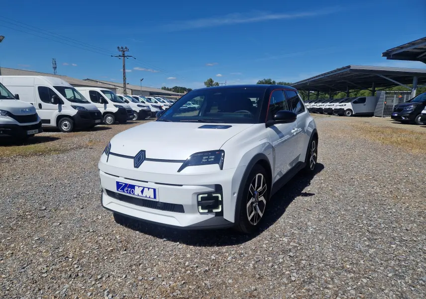 Renault R5 E-TECH blanc nacré et noir en 3/4 avant droit sur parking avec plusieurs fourgons blancs en arrière-plan.