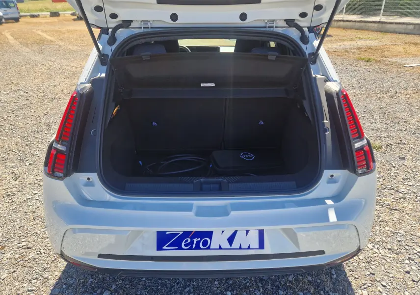 Vue arrière ouverte de la Renault R5 E-TECH blanc nacré/noir, coffre avec câble de recharge visible.
