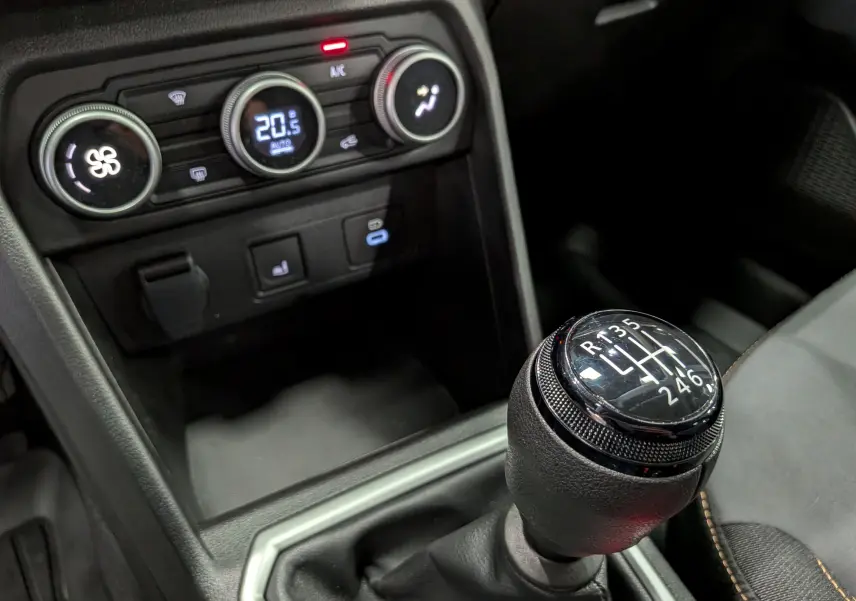 Gros plan sur la commande de la boîte manuelle et la console de climatisation du Dacia Sandero Stepway TCe 110 Gris Schiste.