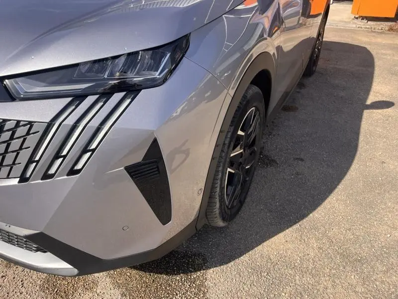 Gros plan sur l'avant droit gris Artense du Peugeot 3008 2025, mettant en valeur le phare LED et la calandre distinctive.