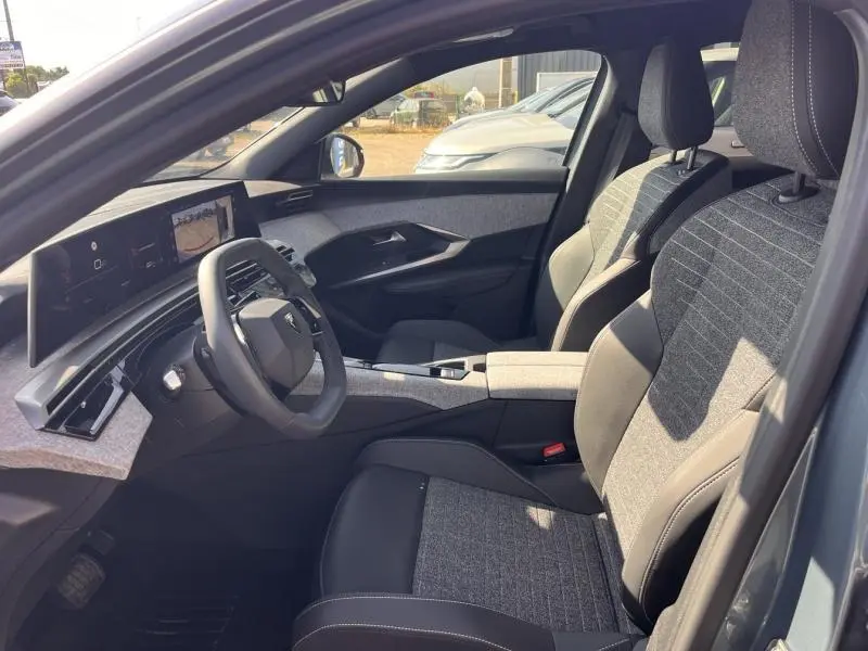 Vue intérieure côté conducteur du Peugeot 3008 gris Artense, mettant en valeur le volant cuir multifonction et les sièges tissu/crispy.