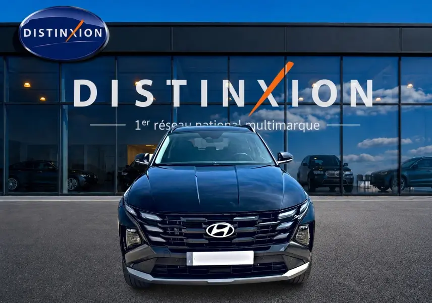 Vue de face d'un Hyundai Tucson noir 2026 avec calandre large et phares LED, devant une vitrine Distinxion.