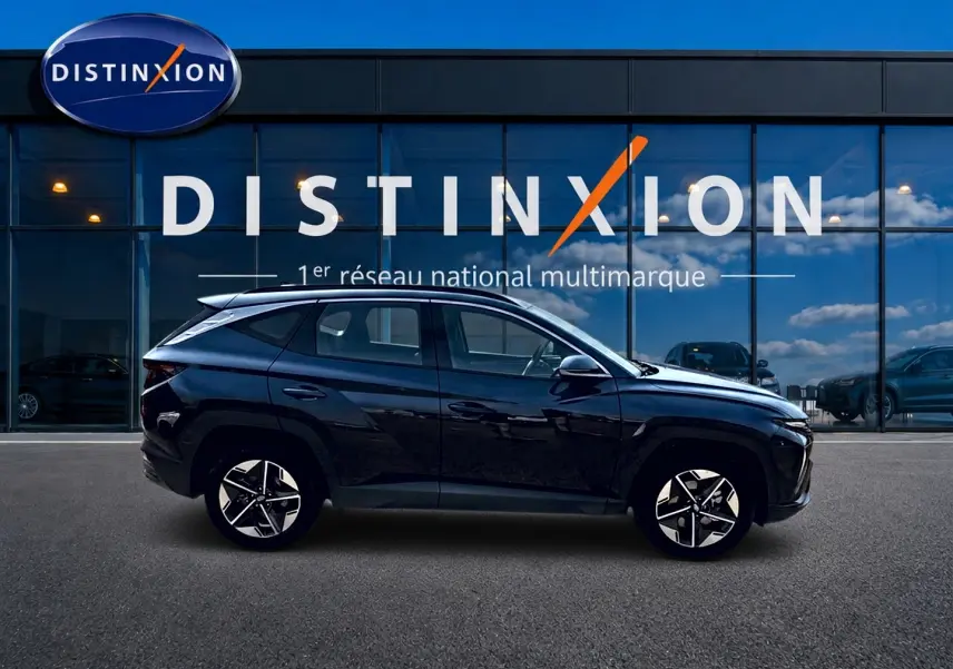 Profil droit du Hyundai Tucson noir 2026 hybride, avec jantes alu et lignes anguleuses modernes, devant une vitrine Distinxion.