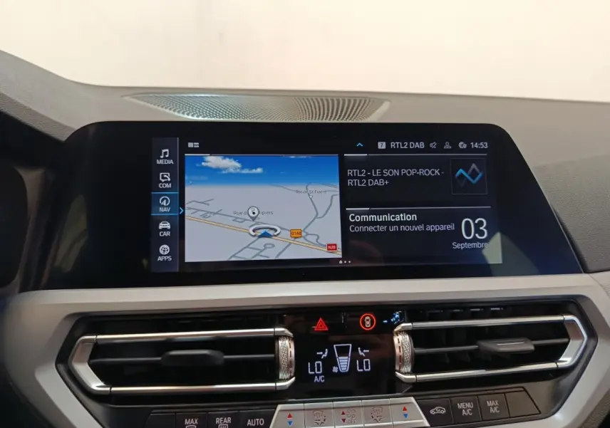 Vue rapprochée de l’écran tactile central et des commandes de climatisation d’une BMW Série 3 320e hybride blanche, intérieur moderne.