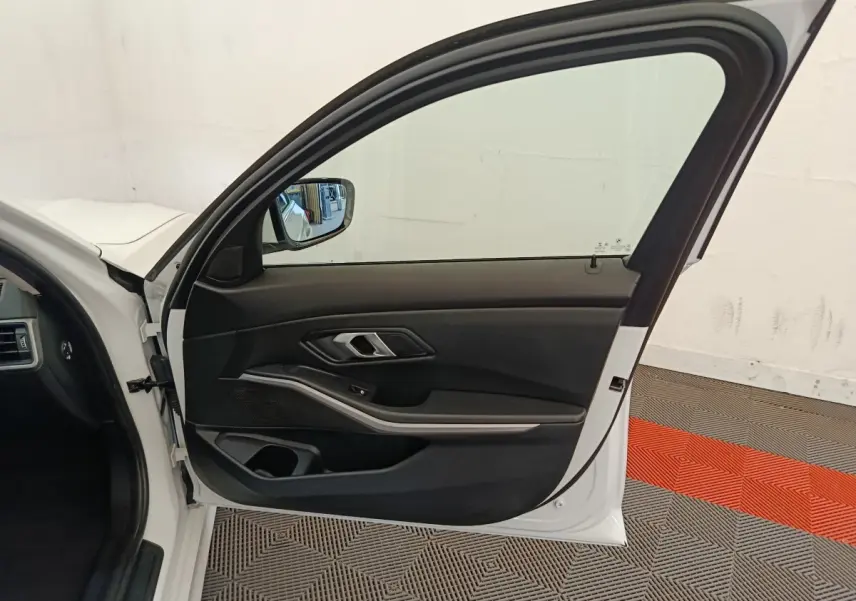 Vue intérieure de la porte avant gauche blanche d'une BMW Série 3 320e hybride, avec garniture noire et insert argenté.