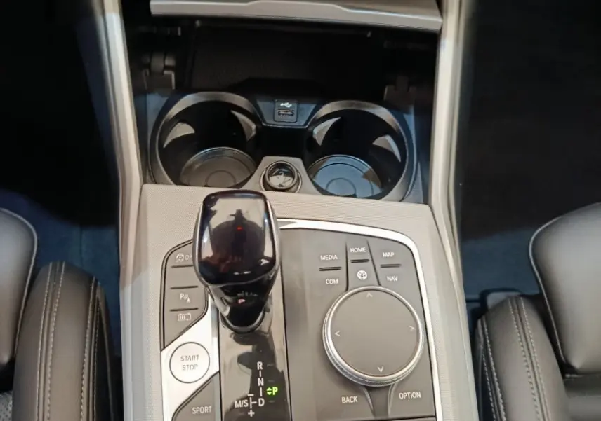 Vue rapprochée de la console centrale noire et argentée de la BMW Série 3 320e hybride avec levier de vitesse et boutons multifonctions.