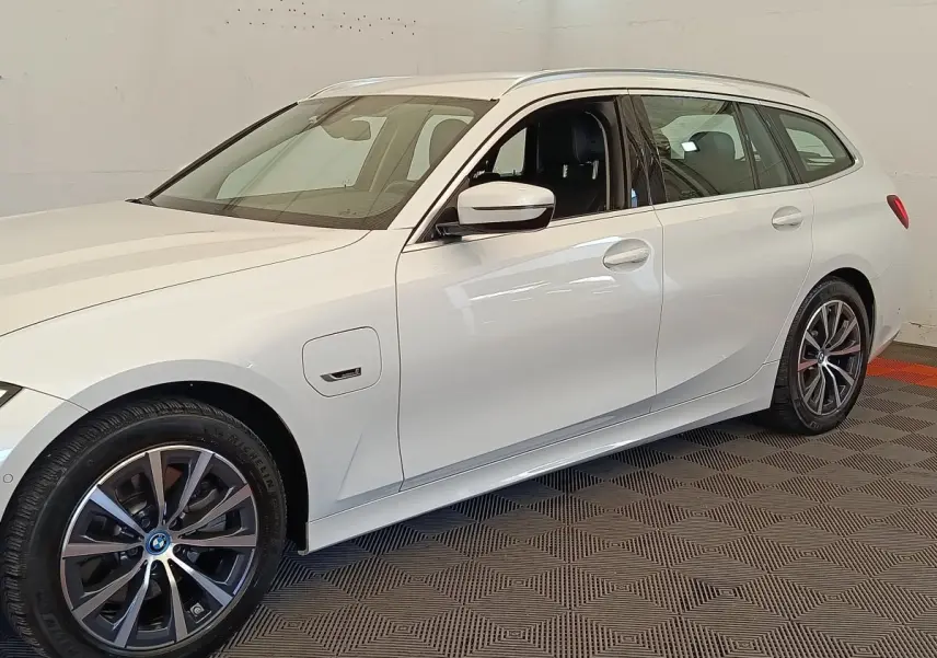 BMW Série 3 320e hybride blanche vue de profil côté gauche, avec jantes alliage et prise de recharge visible.