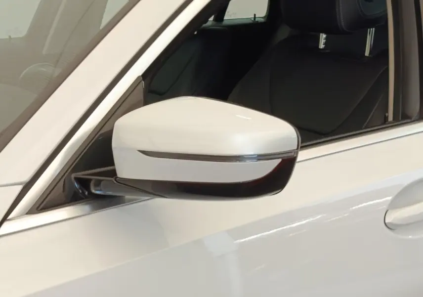Gros plan sur le rétroviseur côté gauche blanc d’une BMW Série 3 320e hybride avec intérieur cuir noir visible.