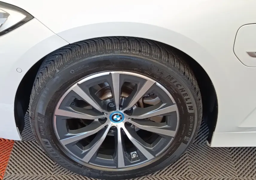 Gros plan sur la roue avant gauche d'une BMW Série 3 320e blanche avec jante alliage distinctive.