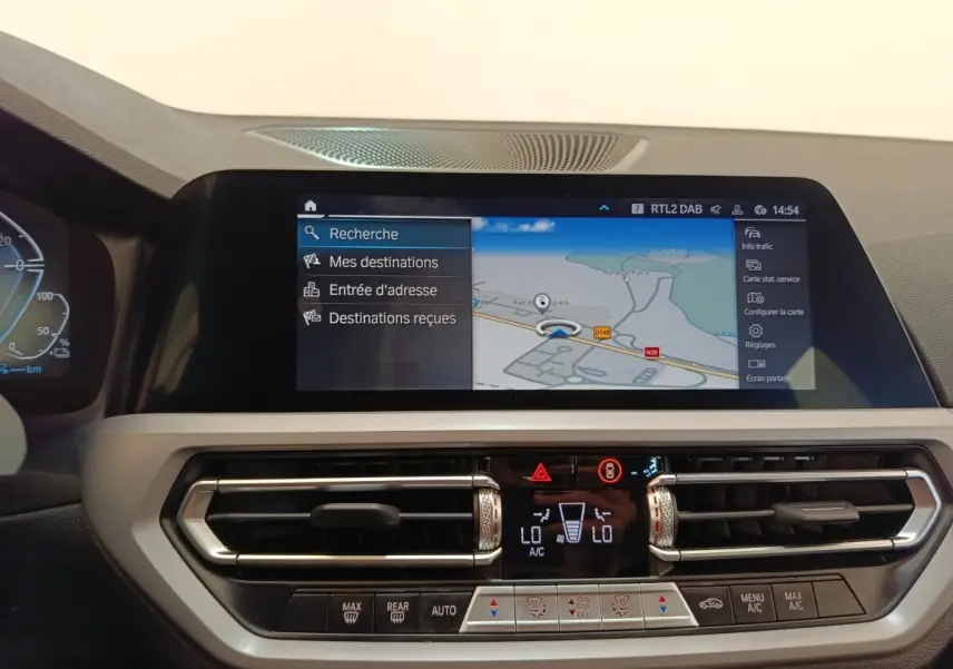 Vue rapprochée de l’écran tactile de navigation 3D et de la console centrale de la BMW Série 3 blanche hybride 320e.