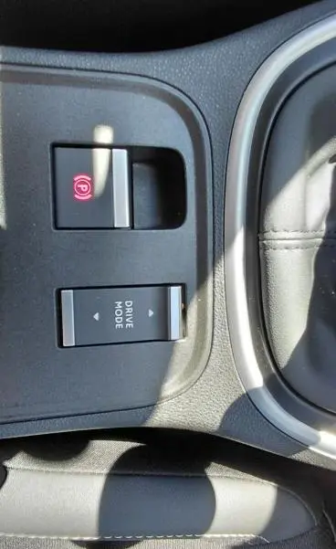 Gros plan sur les commandes de frein à main électronique et mode de conduite du Jeep Avenger 2025, intérieur noir.