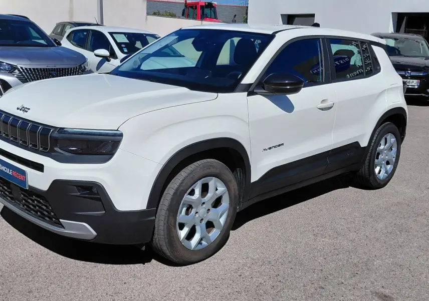 Jeep Avenger blanc en 3/4 avant droit, avec calandre noire distinctive et jantes argentées, stationné en extérieur.