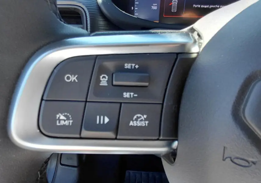 Gros plan sur les commandes au volant du Jeep Avenger blanc 2025, avec boutons de régulateur et assistance.