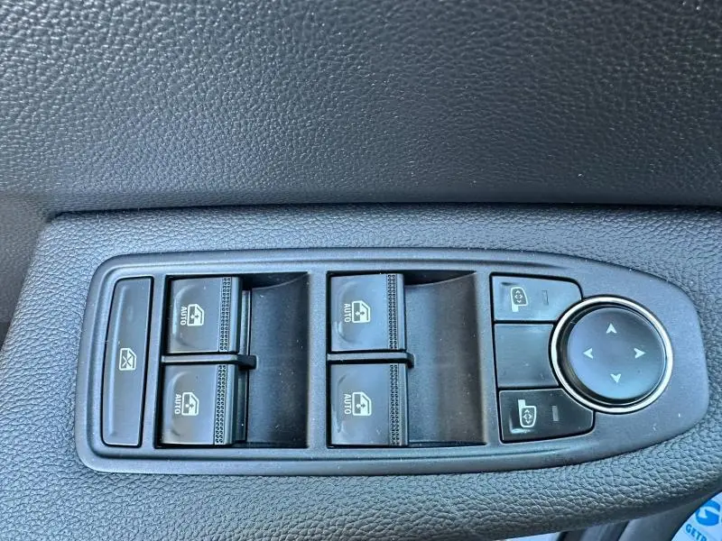 Gros plan sur les commandes de lève-vitres et réglage des rétroviseurs côté conducteur d'une Renault Clio gris Rafale.
