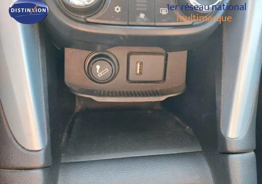 Prise allume-cigare et port USB sur la console centrale de l'Opel Zafira noire métal, vue rapprochée intérieure.