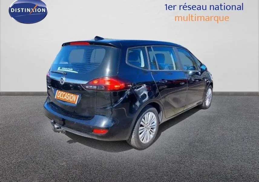 Opel Zafira noir métal en 3/4 arrière droit, montrant ses feux arrière et hayon avec attelage visible.