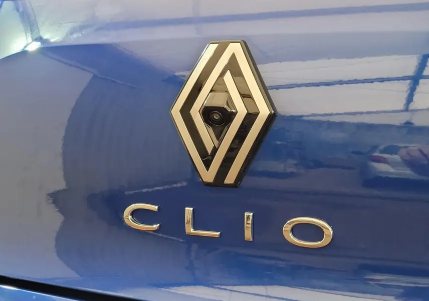 Gros plan sur l'arrière bleu d'une Renault Clio avec logo et caméra intégrée au centre du losange.