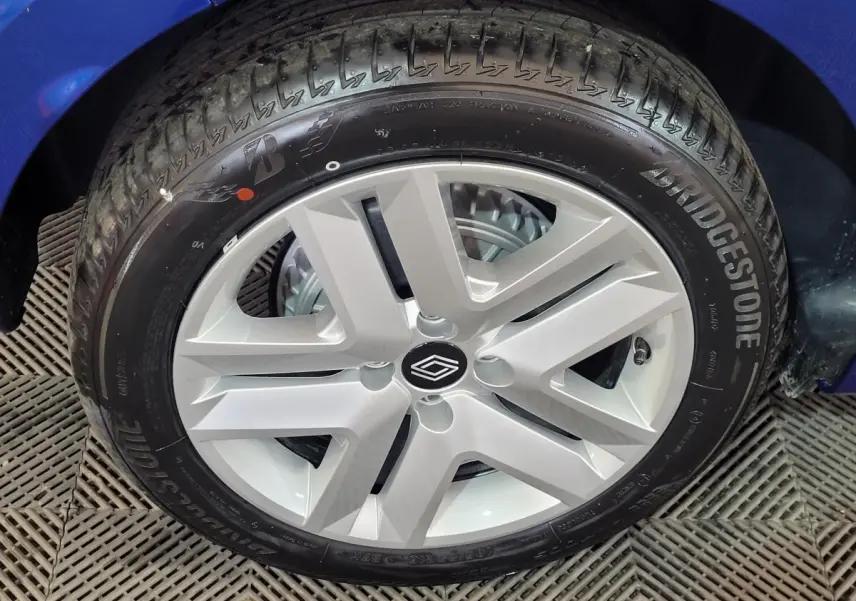Gros plan sur la roue avant gauche d'une Renault Clio bleu, avec jante argentée au design moderne et pneu Bridgestone.