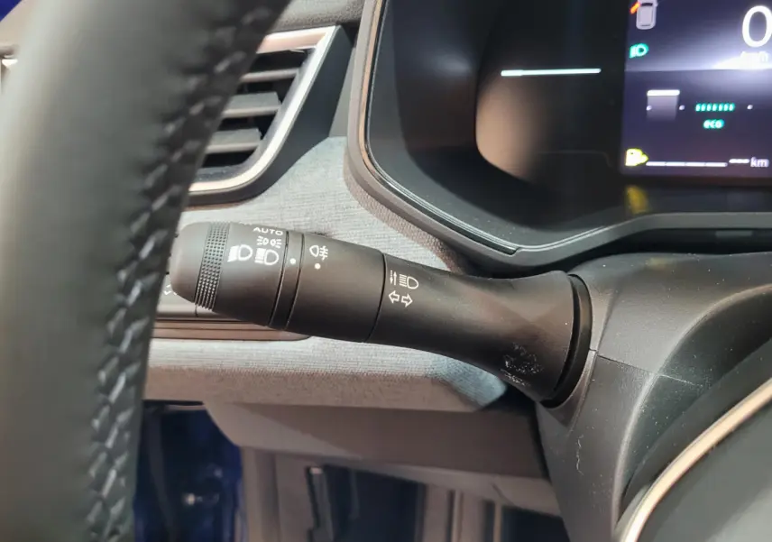 Le commodo d'éclairage noir avec commandes LED sur le tableau de bord d'une Renault Clio bleu 2025.