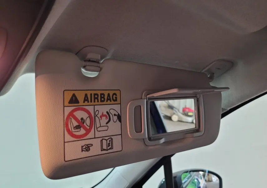 Détail du pare-soleil côté conducteur avec miroir ouvert et avertissement airbag dans une Renault Clio bleu 2025.