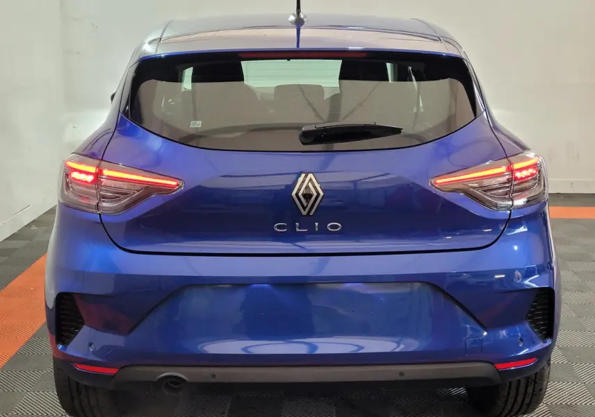 Vue arrière d'une Renault Clio bleu électrique 2025 avec feux LED allumés et logo centré sur le hayon.